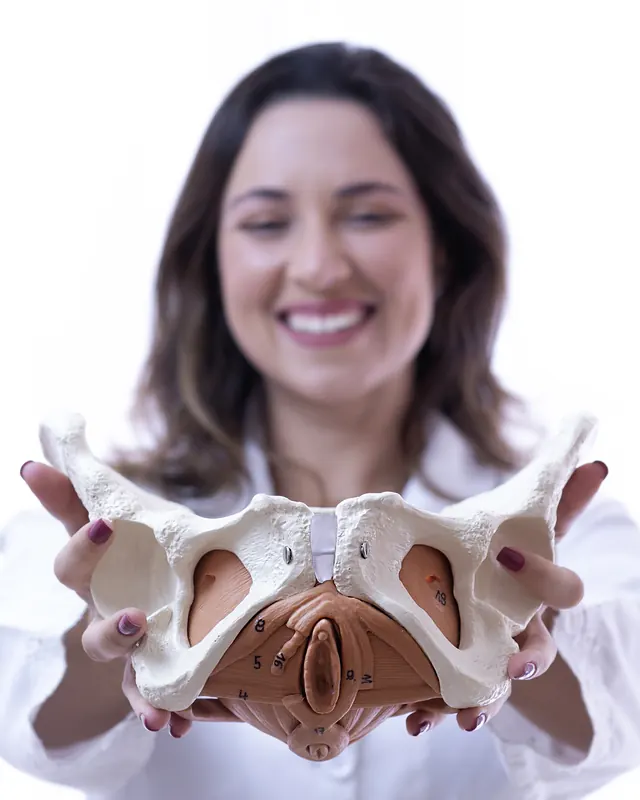 Priscilla segurando uma pelve anatômica em direção à câmera