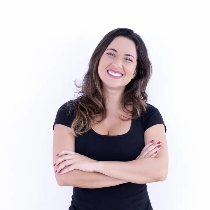 Retrato de Priscilla Valadares sorrindo, de camiseta preta e braços cruzados